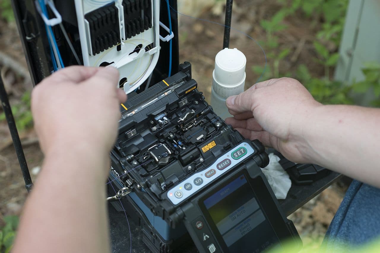 A technician fusion-splicing optical fibre in the field