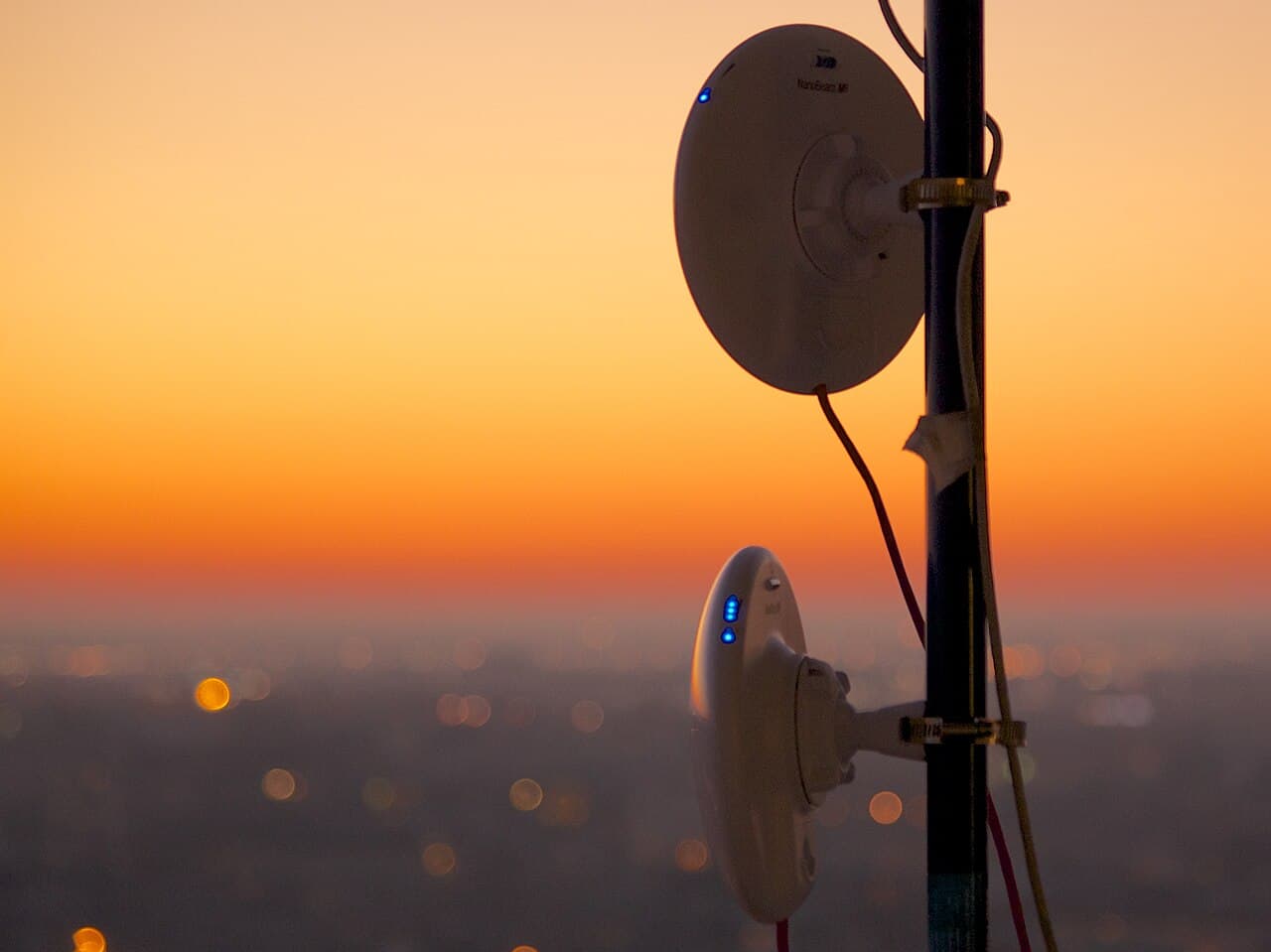 Wireless ISP antennas on a mast above a city at sunset