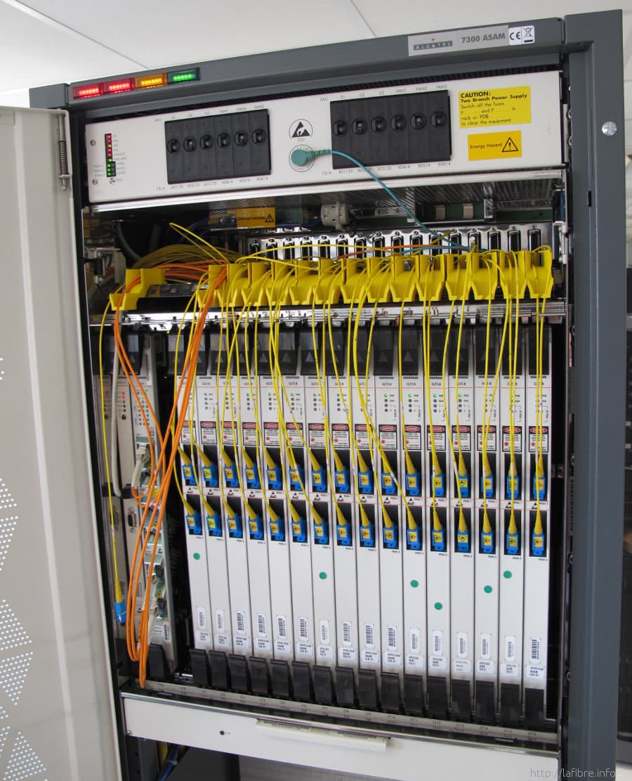 A rack-mounted optical line terminal with a row of fibre line cards and yellow patch cords